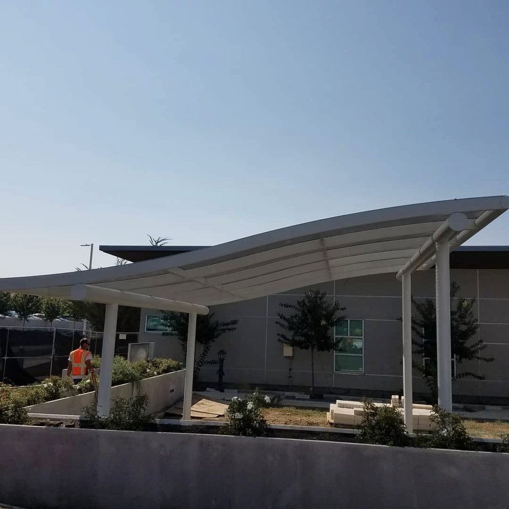 White curved steel shade canopy over a courtyard