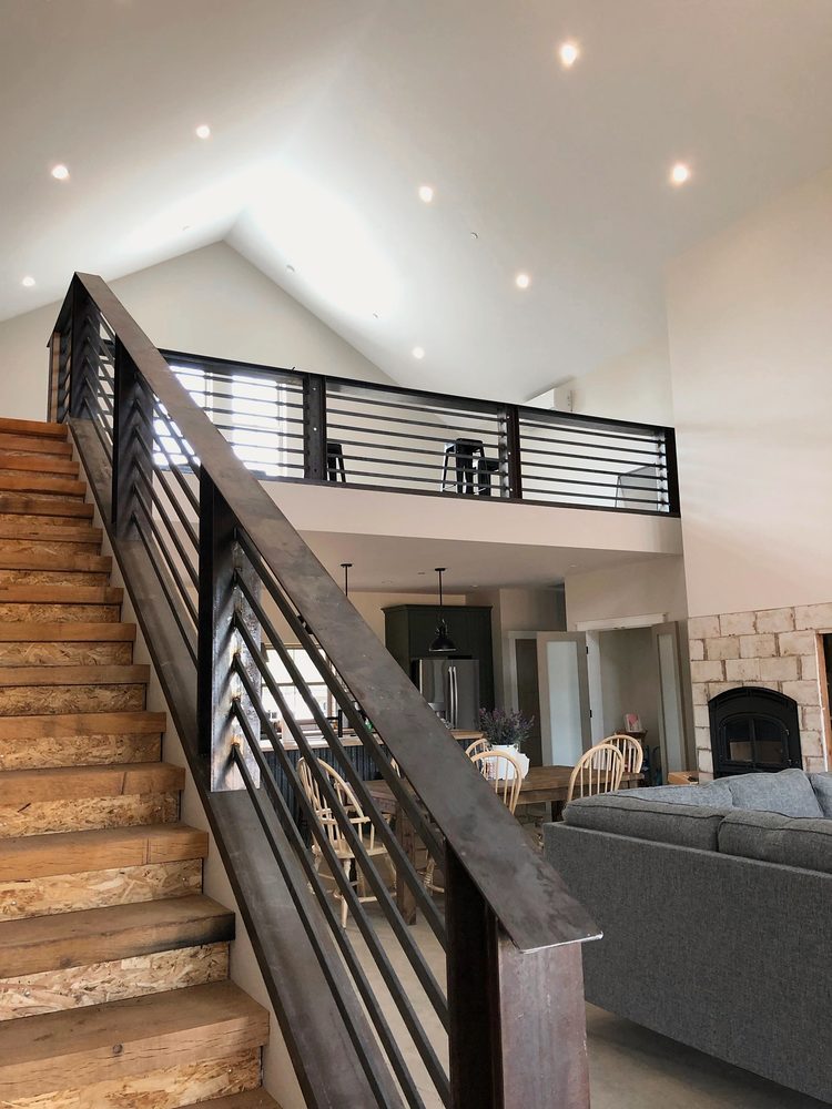 Blackened steel stair railing with horizontal bars, running up to a matching loft railing